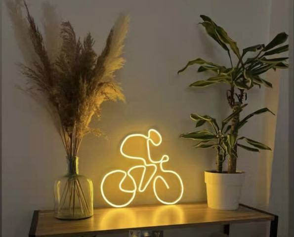 Néon LED en forme de cycliste, ambiance chaleureuse posé sur un meuble